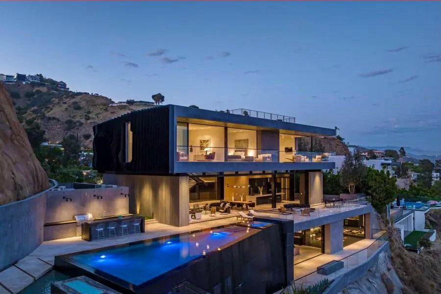 Hillside residence lit from within at blue hour